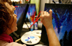 mujer feliz pintando un cuadrode una noche estrellada